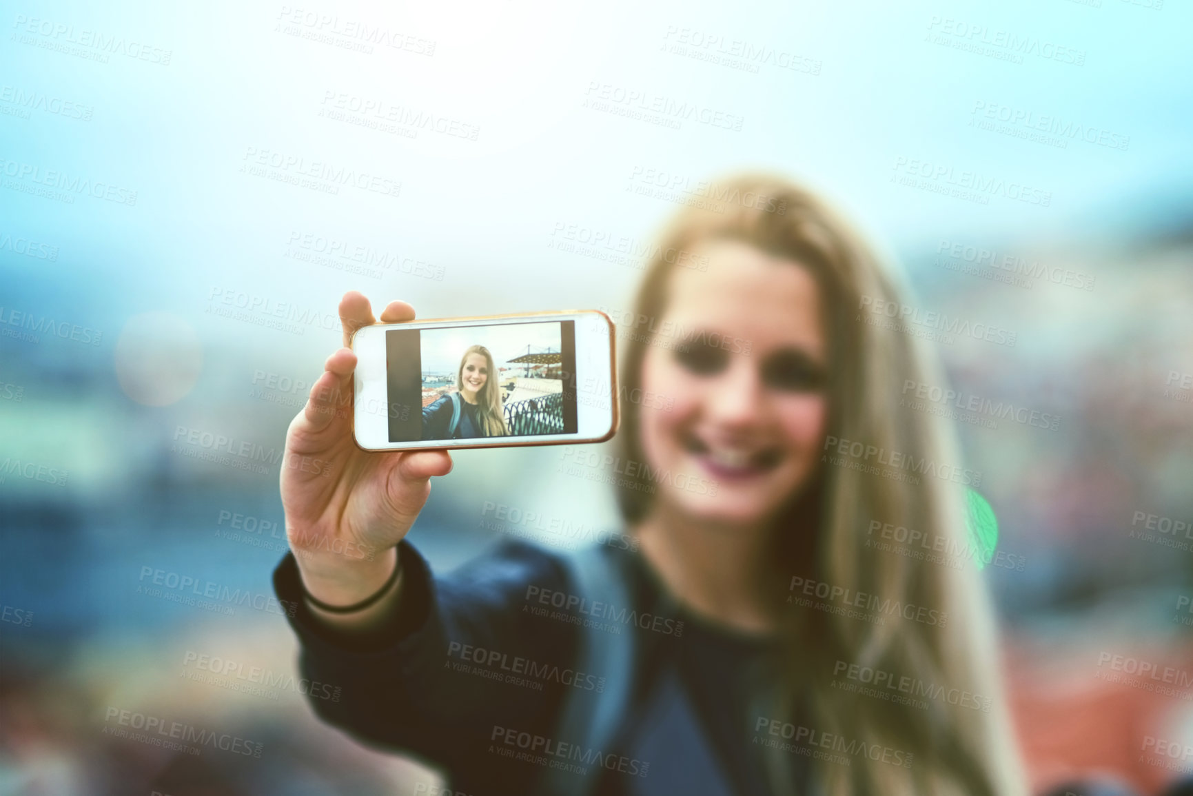 Buy stock photo Shot of a young woman using a cellphone to take selfies in the city
