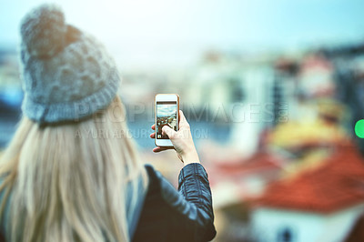 Buy stock photo Rearview shot of a young woman using a cellphone to take pictures of a city view