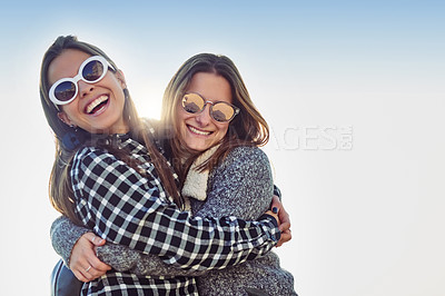 Buy stock photo Cropped portrait of two attractive young women embracing while standing outdoors