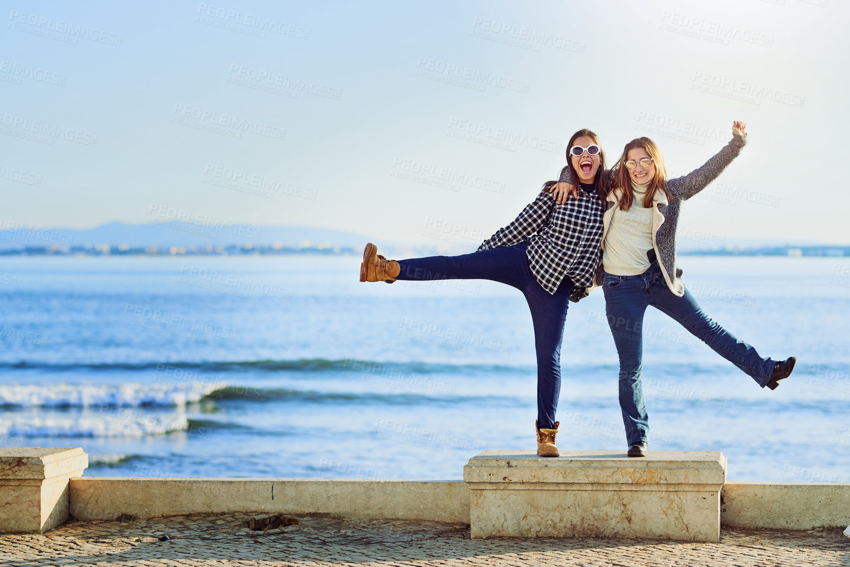 Buy stock photo Full length portrait of two attractive young women spending a day by the ocean