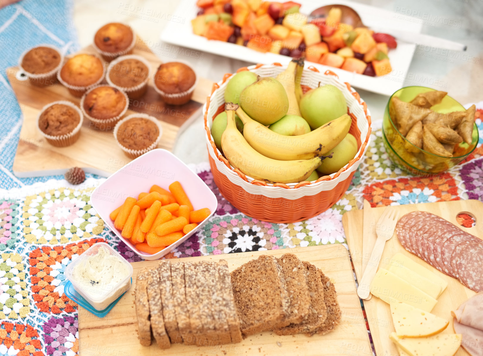 Buy stock photo Shot of a spread of different types of snacks placed together on a picnic blanket outside during the day