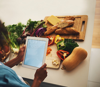 Buy stock photo Shot of an unrecognizable person holding a digital tablet over a bunch of vegetables in the kitchen at home