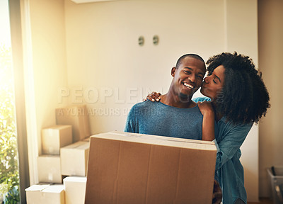 Buy stock photo Portrait of a cheerful young man carrying a cardboard box while his girlfriend gives him a kiss on the cheek