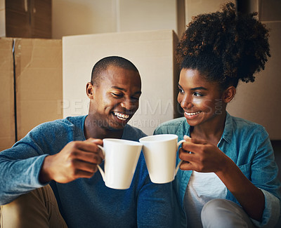 Buy stock photo Shot of a cheerful young couple  enjoying a cup of coffee together while being surrounded by cardboard boxes inside at home