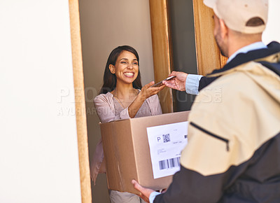 Buy stock photo Shot of a young woman using a digital tablet to sign for her delivery from the courier