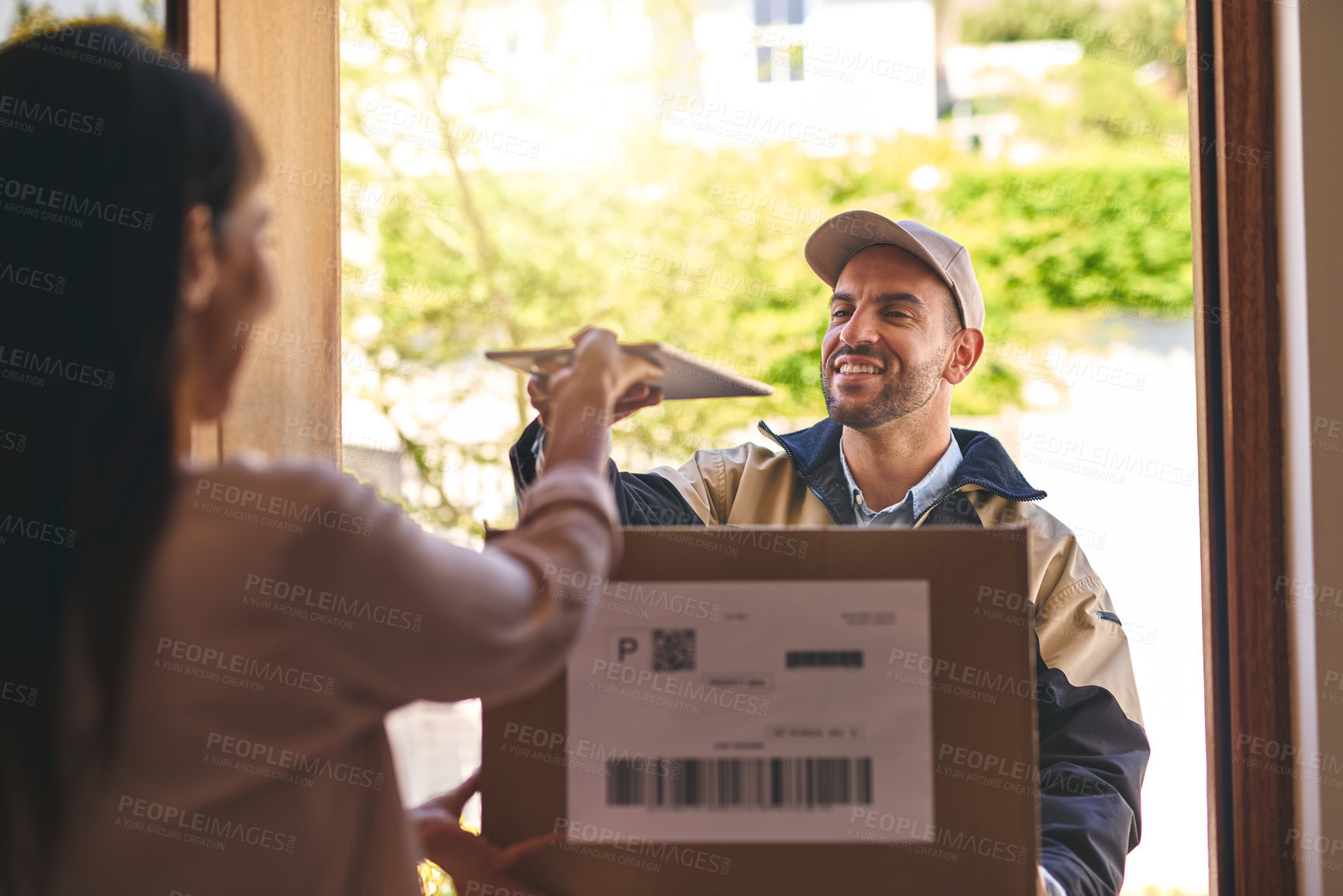 Buy stock photo Shot of a courier handing over a digital tablet to a customer to sign for her delivery