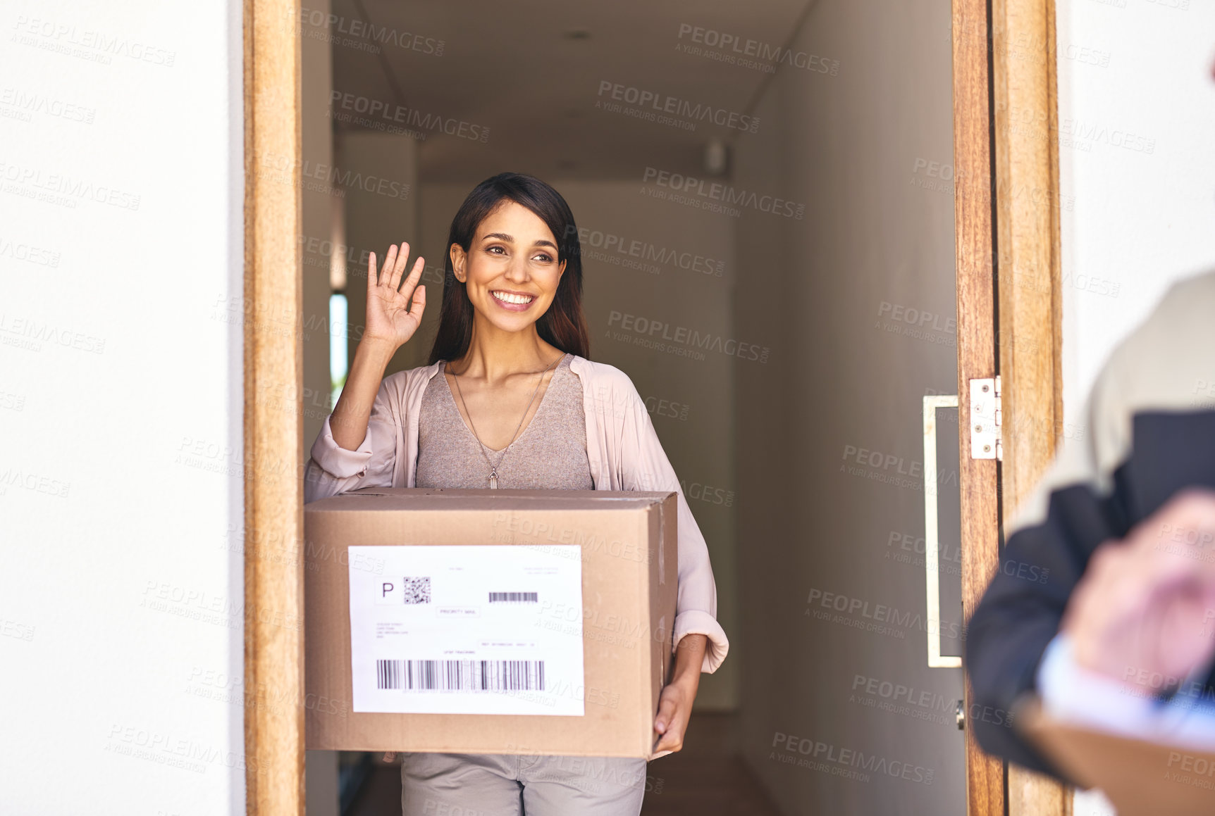 Buy stock photo Shot of a young woman waving goodbye to a delivery man