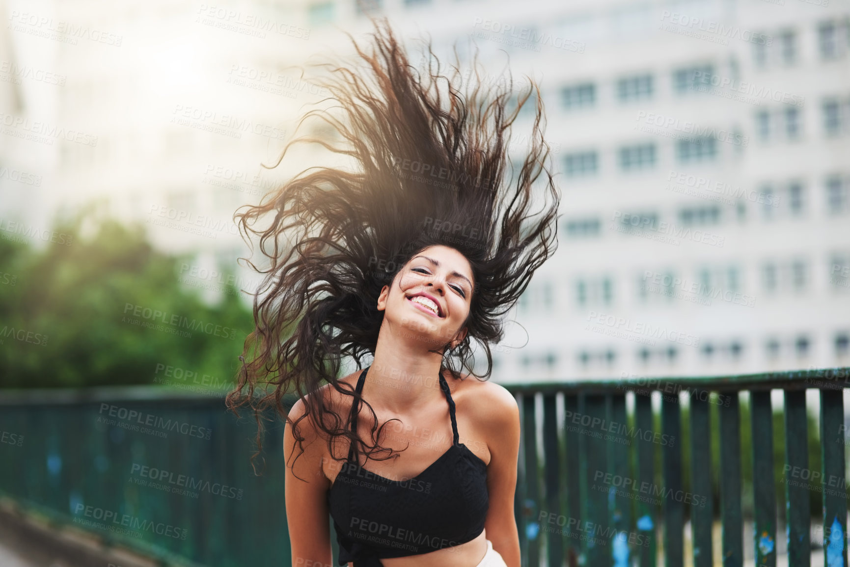 Buy stock photo Portrait of an attractive young woman tossing her hair while out in the city