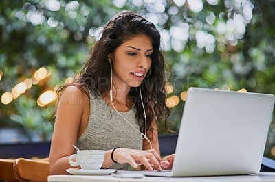 Buy stock photo Shot of an attractive young woman using a laptop at a cafe