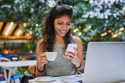 Buy stock photo Shot of a young woman using a cellphone and laptop at a cafe