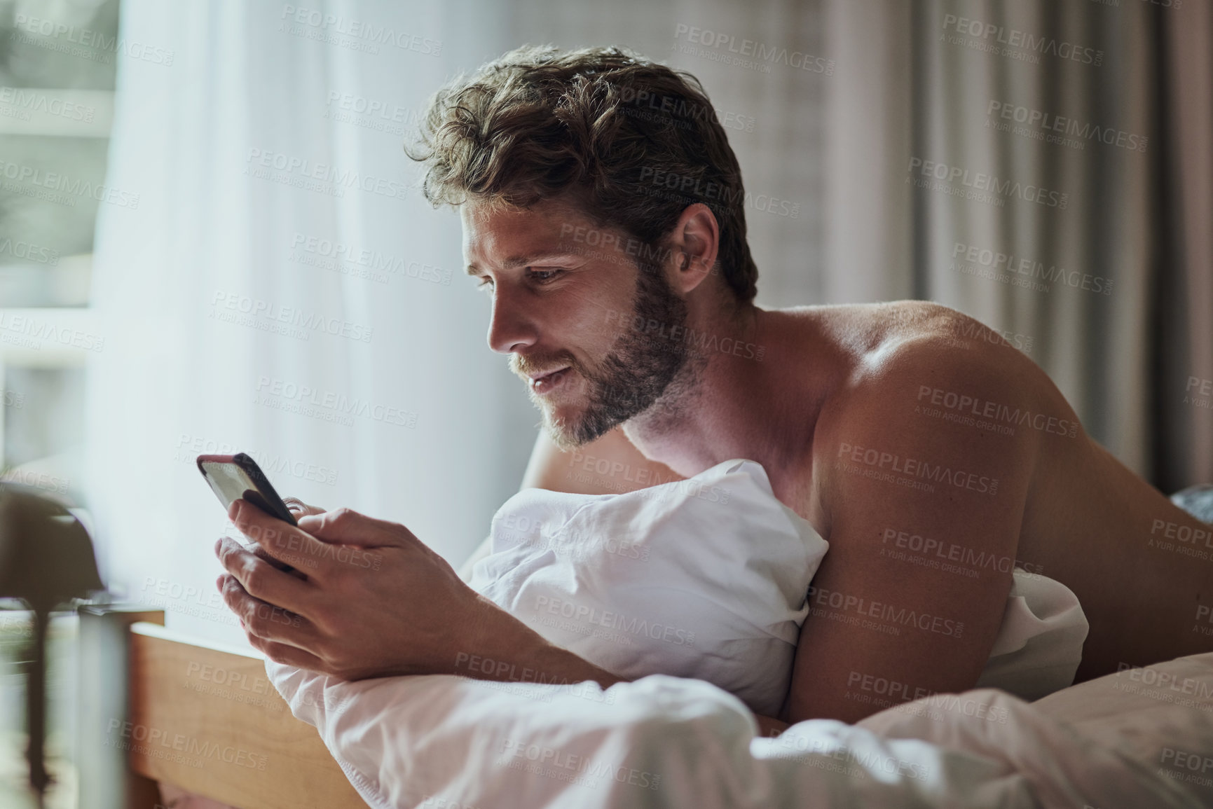 Buy stock photo Man, phone and shirtless on bed in home, reading and texting with scroll on mobile app in morning. Person, smartphone and wake up in bedroom, search or check notification on social network in house