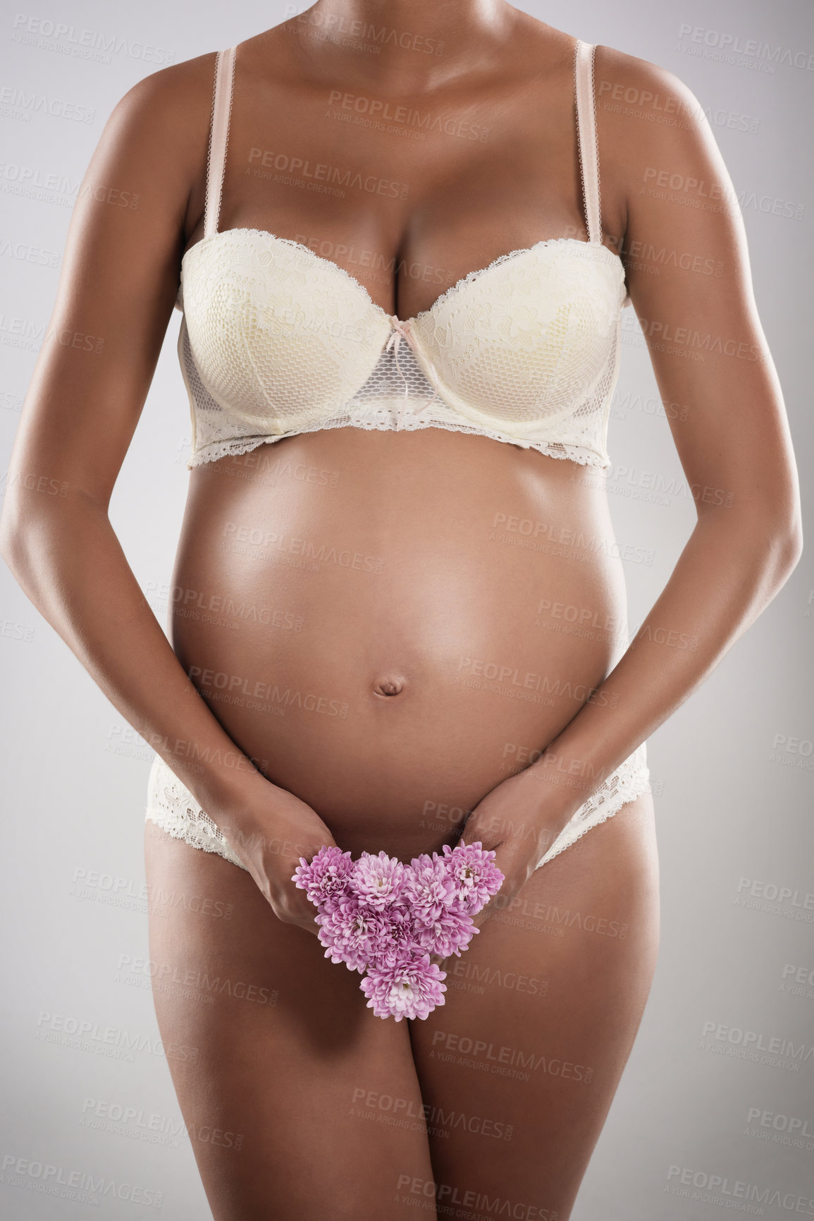 Buy stock photo Studio shot of an unrecognizable pregnant woman holding flowers against a gray background
