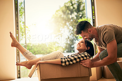 Buy stock photo New home, smile and couple pushing box, having fun and bonding in apartment. Real estate, happiness and man and woman in cardboard, play and enjoying quality time together while moving into property.