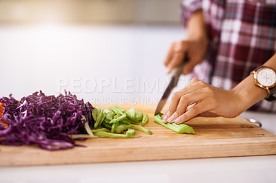Buy stock photo Cropped shot of an unrecognizable woman cutting vegetables in the kitchen at home