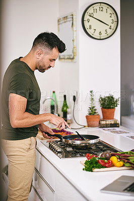 Buy stock photo Cropped shot of a handsome young man cooking in the kitchen at home