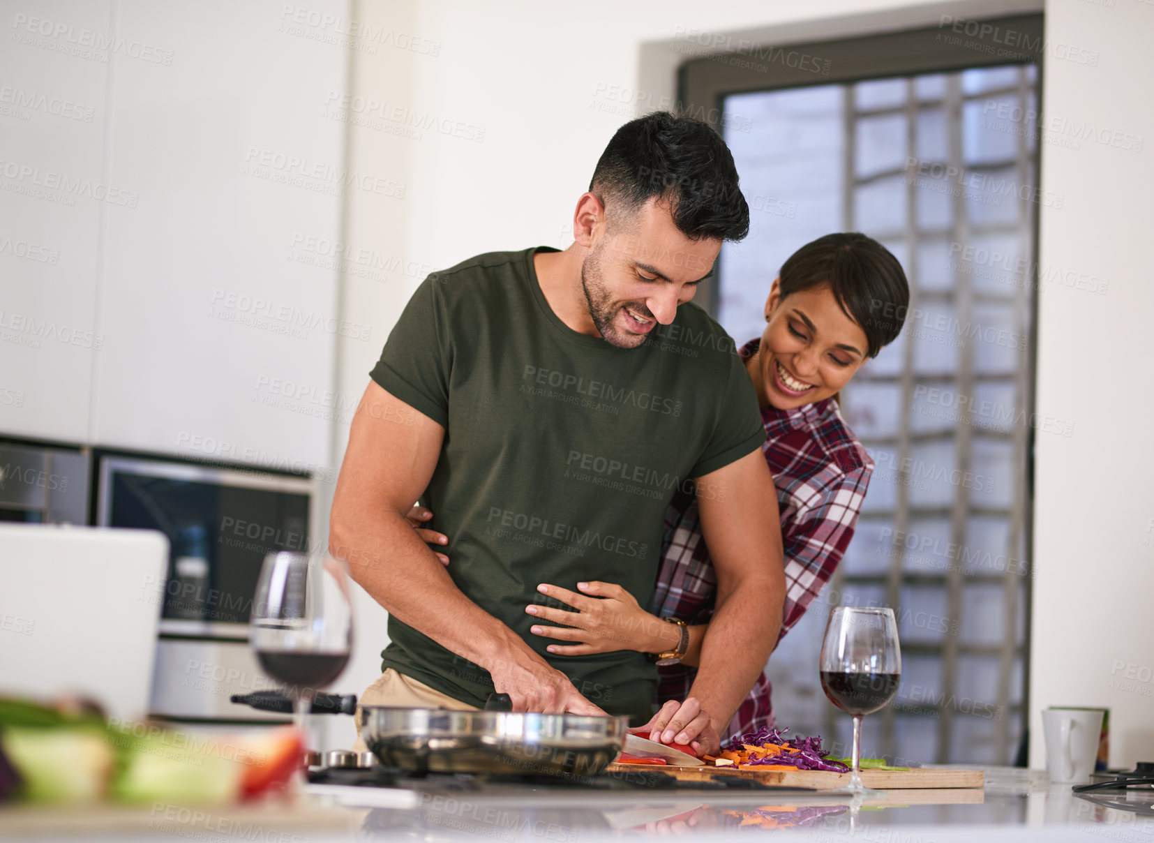 Buy stock photo Cropped shot of a young attractive couple cooking together in the kitchen at home