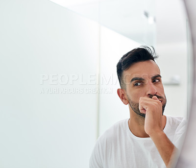 Buy stock photo Shot of a handsome young man brushing his teeth in the bathroom