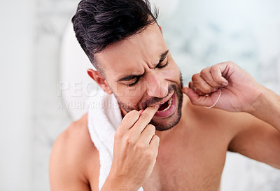Buy stock photo Shot of a handsome young man flossing his teeth in the bathroom