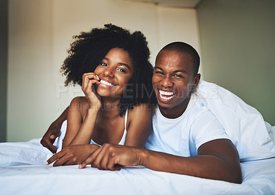 Buy stock photo Portrait of a happy young couple relaxing under a duvet in their bedroom