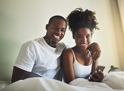 Buy stock photo Portrait of a happy young couple using a mobile phone together in bed at home