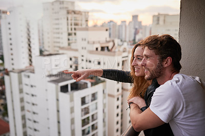 Buy stock photo Cropped shot of an attractive young couple on a rooftop looking over the city