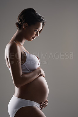 Buy stock photo Studio shot of a beautiful young pregnant woman posing in underwear against a gray background