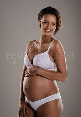 Buy stock photo Studio portrait of a beautiful young pregnant woman posing in underwear against a gray background