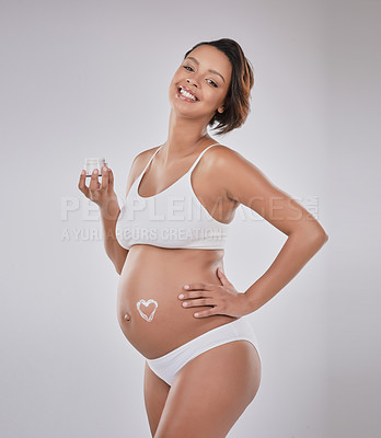 Buy stock photo Studio portrait of a beautiful young pregnant woman with moisturizer in the shape of a heart on her belly