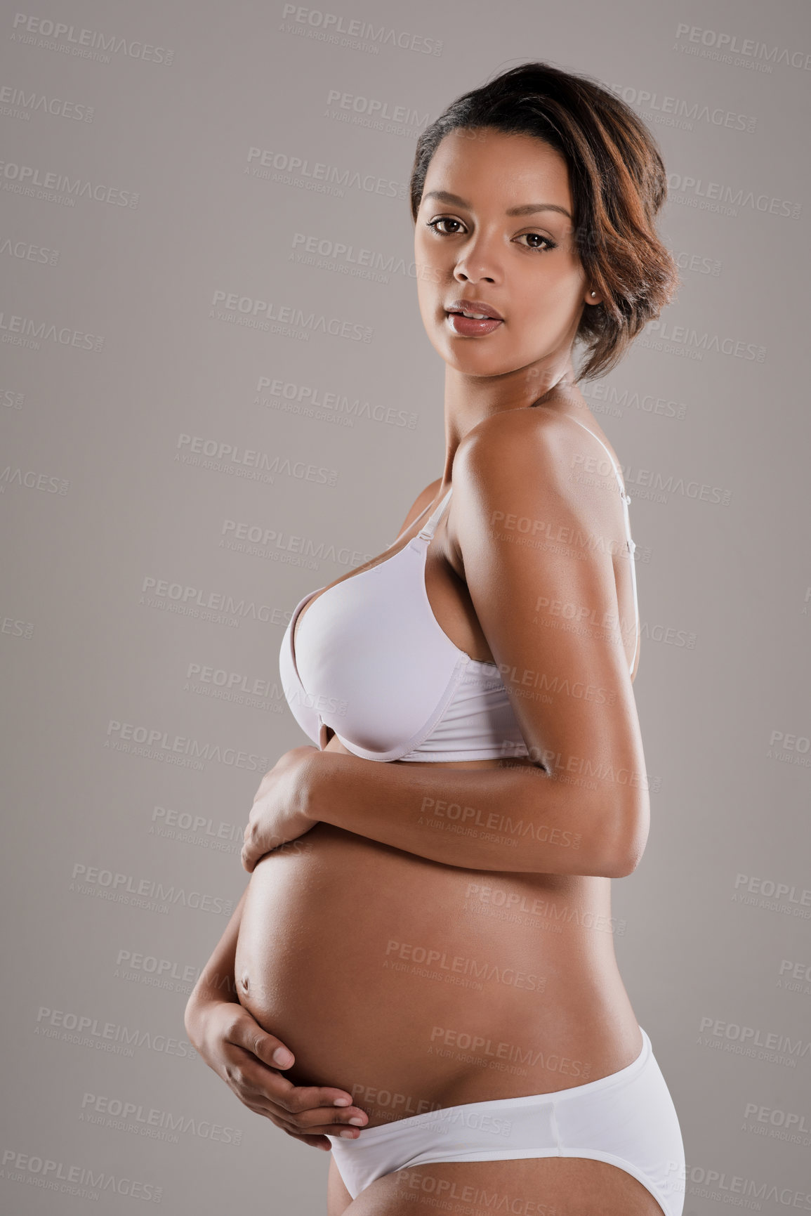 Buy stock photo Woman, portrait and underwear for pregnant, motherhood and stomach growth with prenatal care in studio. Female person, face and lingerie on gray background for pregnancy, maternity and gynecology