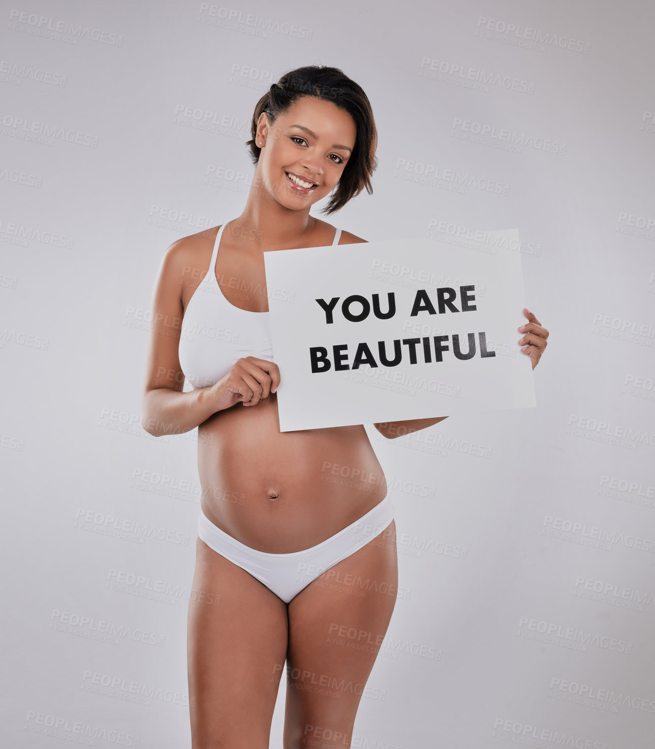 Buy stock photo Studio portrait of a beautiful young pregnant woman holding a sign with the word, “You are beautiful” on it