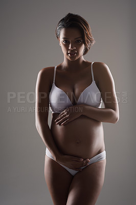 Buy stock photo Studio portrait of a beautiful young pregnant woman posing in underwear against a gray background