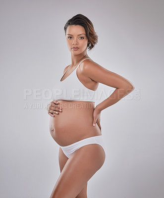 Buy stock photo Studio portrait of a beautiful young pregnant woman posing against a gray background