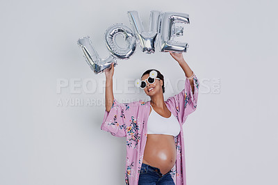 Buy stock photo Studio shot of a beautiful young pregnant woman holding up a word balloon that reads 'love' against a gray background