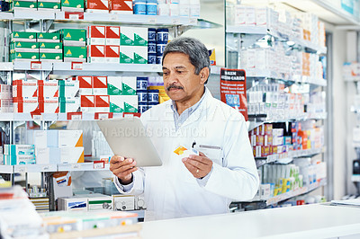 Buy stock photo Shot of a mature pharmacist using a digital tablet in a chemist