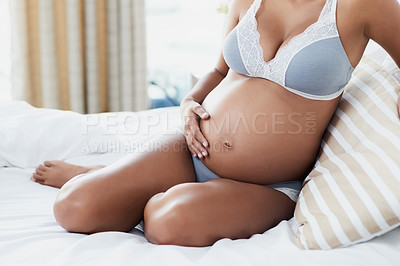 Buy stock photo Shot of a pregnant young woman relaxing on her bed at home