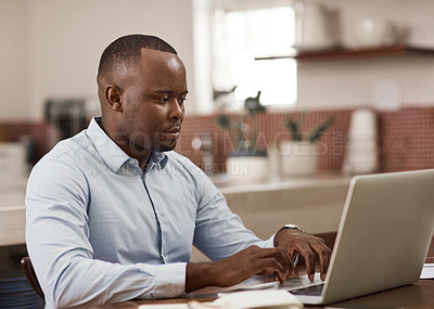 Buy stock photo Cropped shot of a handsome young businessman working on his laptop at home