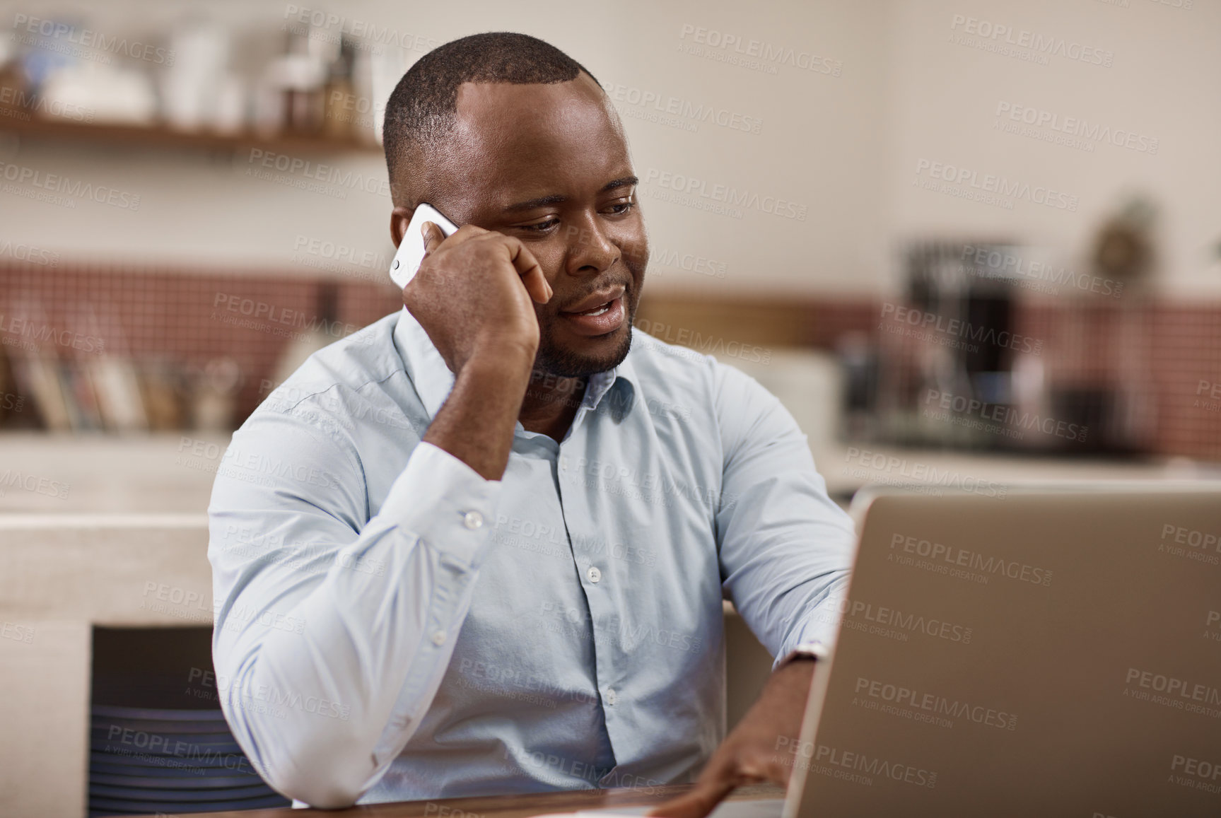 Buy stock photo Cropped shot of a handsome young businessman making a phonecall while working on his laptop at home