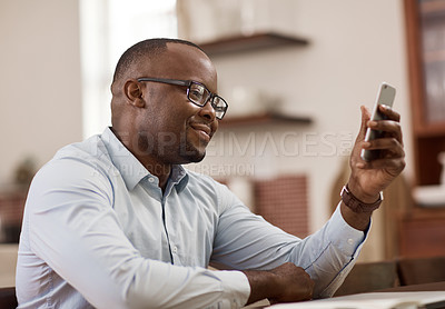 Buy stock photo Cropped shot of a handsome young businessman sending a text message while working at home
