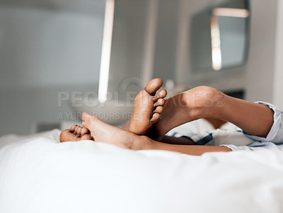 Buy stock photo Shot of an unrecognizable couple's feet resting on each other on a bed in the morning at home