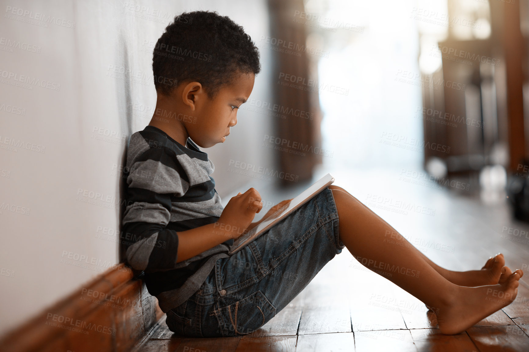 Buy stock photo Full length shot of a young boy using his digital tablet while sitting on the floor at home