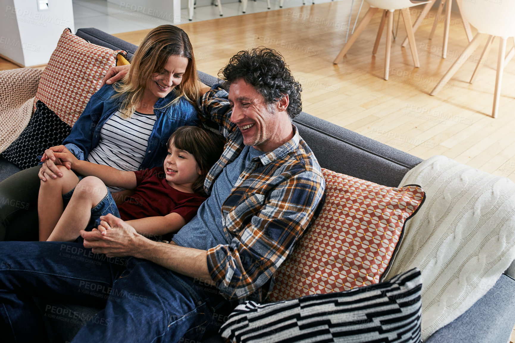 Buy stock photo Mom, dad and child smile on sofa in living room for love, care and fun quality time together in family home. Happy young boy, cute kid and relax with parents in lounge, happiness and bonding on couch