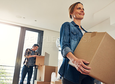 Buy stock photo Shot of a cheerful middle aged couple packing out a boxes at their new home inside during the day