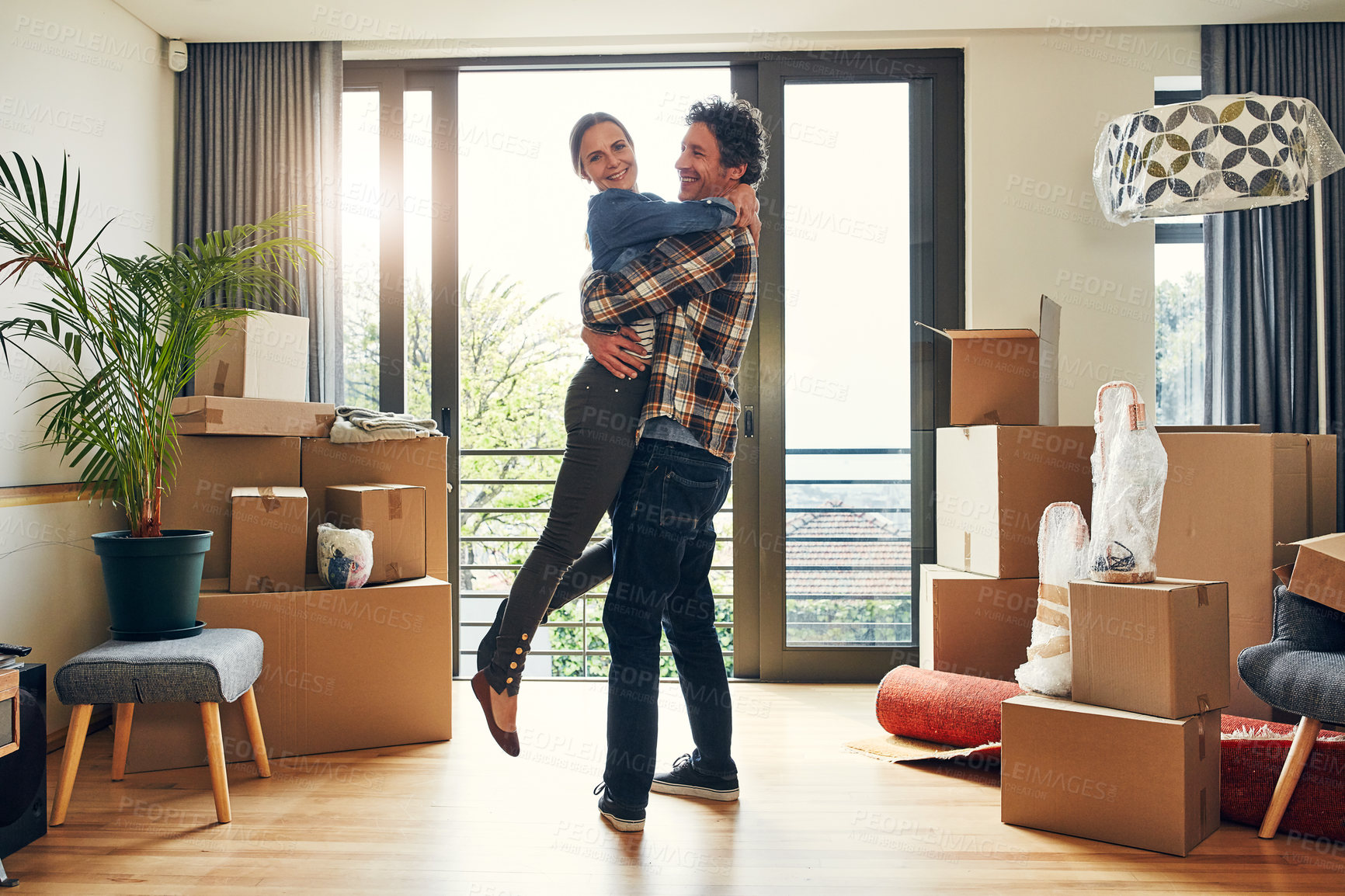 Buy stock photo Portrait of a cheerful middle aged couple holding each other in excitement after moving into their new home inside during the day