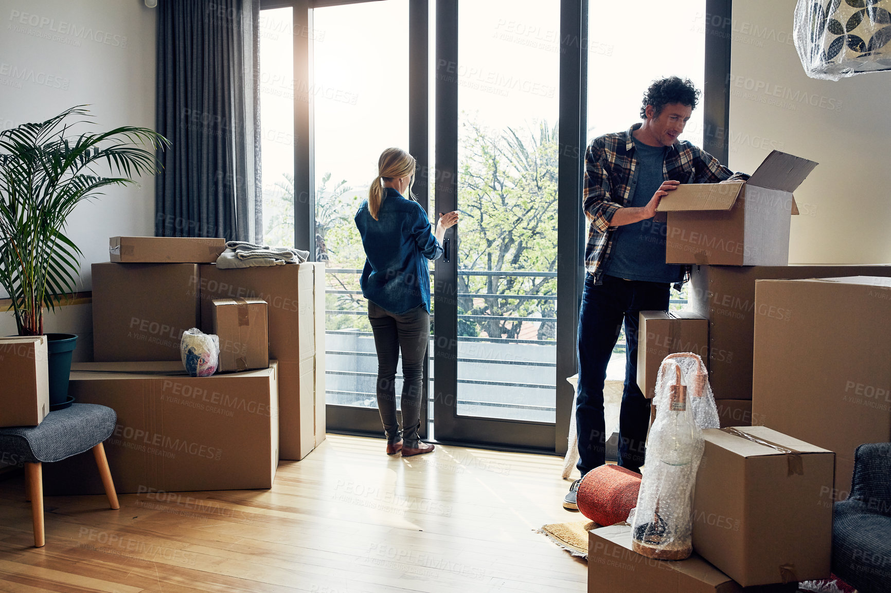 Buy stock photo Shot of a focused middle aged couple packing out a boxes at their new home inside during the day