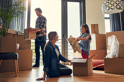 Buy stock photo Shot of a cheerful loving family packing out boxes together in their new home during the day