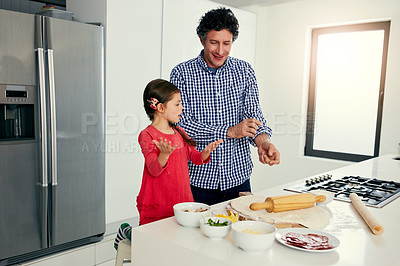 Buy stock photo Shot of a middle aged father and his daughter preparing a pizza to go into the oven in the kitchen at home