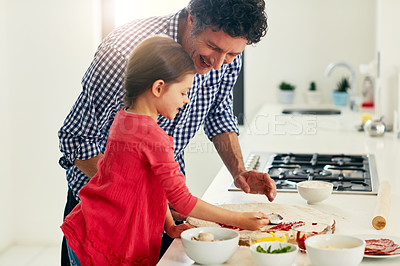 Buy stock photo Shot of a middle aged father and his daughter preparing a pizza to go into the oven in the kitchen at home