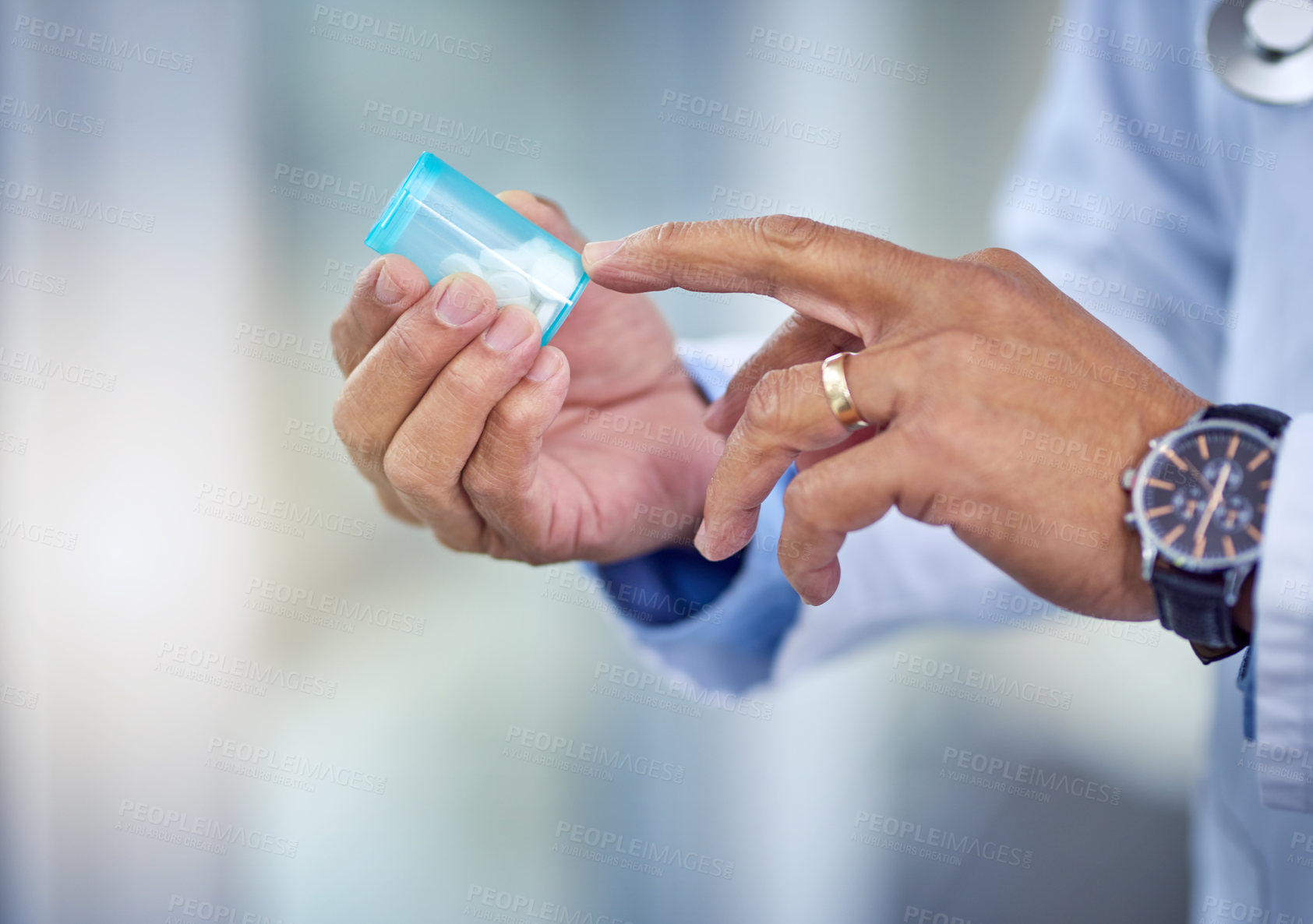 Buy stock photo Shot of an unrecognizable male doctor's hands holding a pill container inside of a hospital during the day