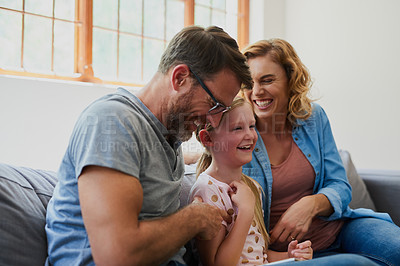 Buy stock photo Cropped shot of a mother and father  tickling their adorable daughter on the sofa at home