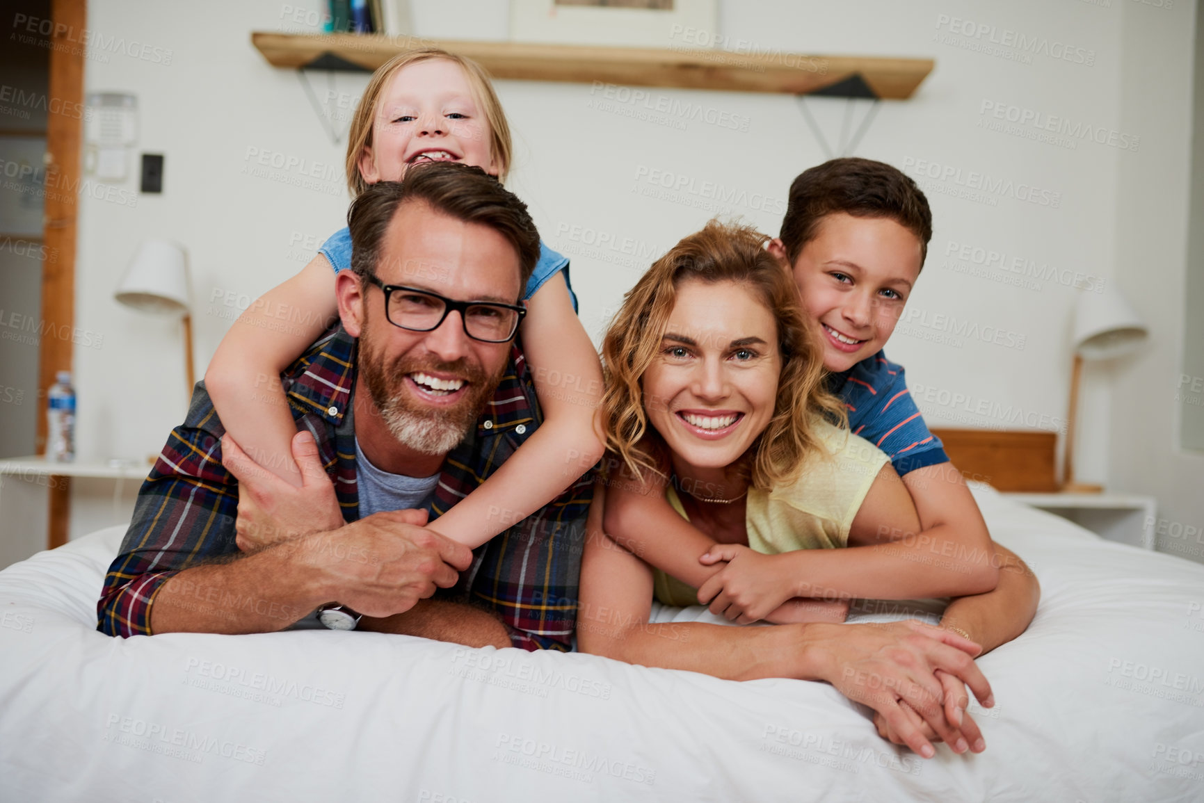 Buy stock photo Portrait of a happy affectionate family lying on the bed in the bedroom at home
